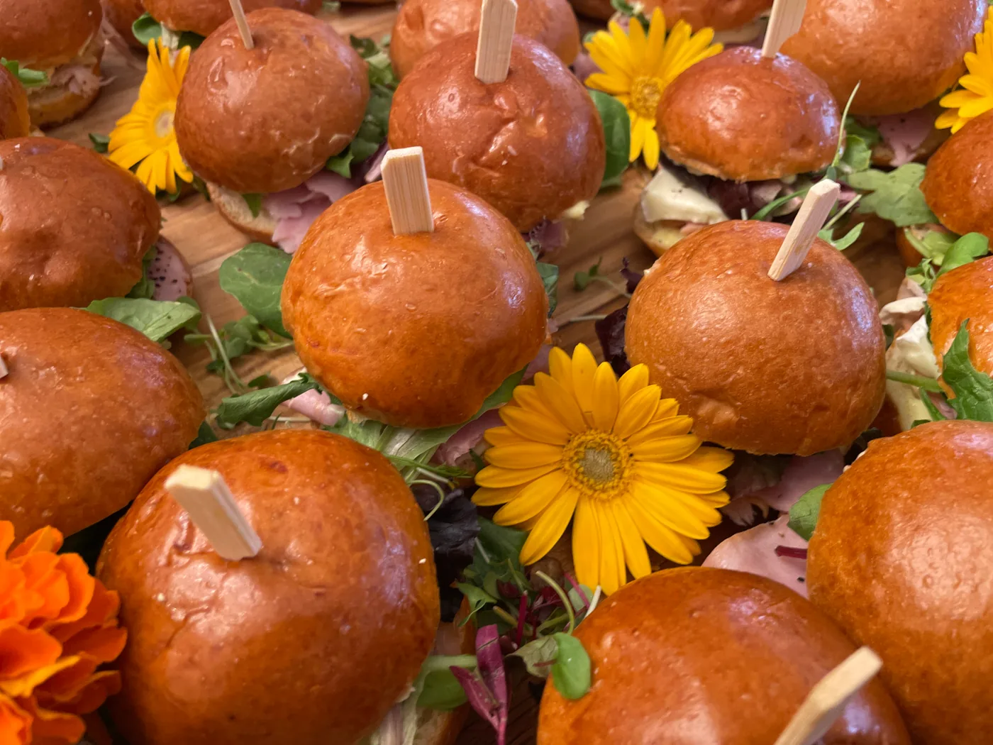 Skewered brioche sliders garnished with fresh orange and yellow flowers